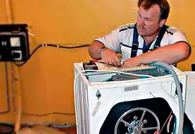Мастер разбирает стиральную машину в ремонт